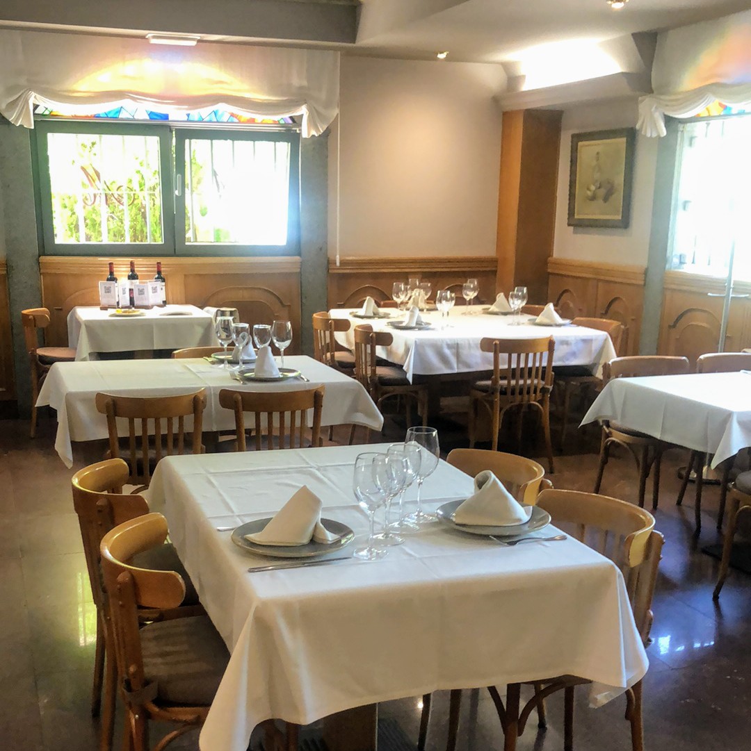 Comedor de Asador Molinero: mesas puestas, paredes en rojo y vidrieras.