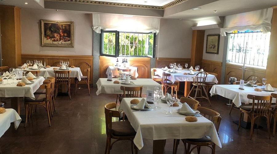 Salón de Asador Molinero, mesas con mantel blanco y sillas de madera.