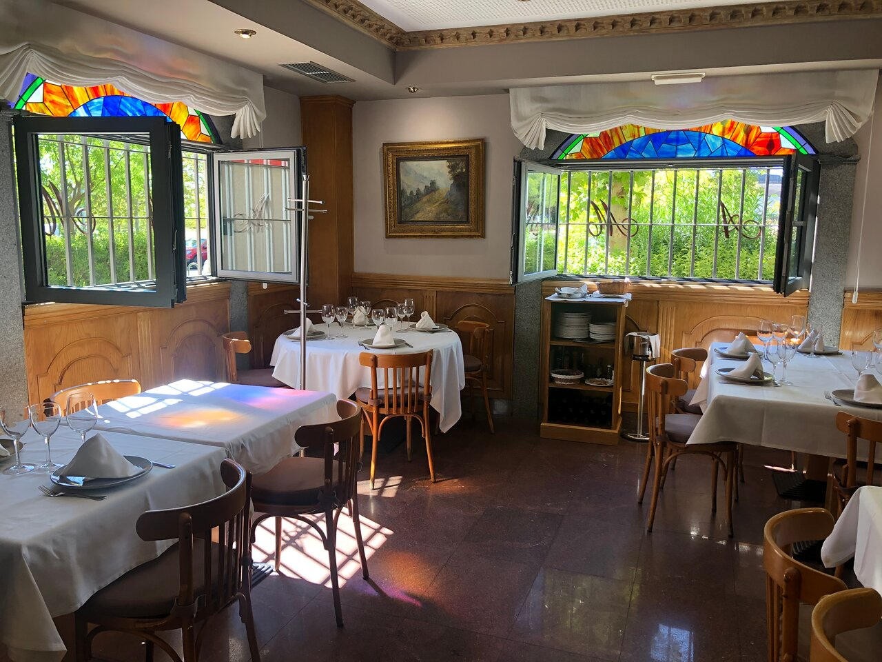 Comedor de Asador Molinero, con vidrieras y mesas puestas.